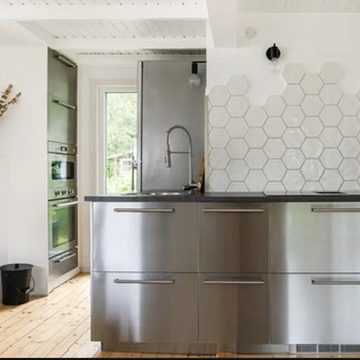 Moderne Küche mit Edelstahloberflächen und Holzdielenboden.