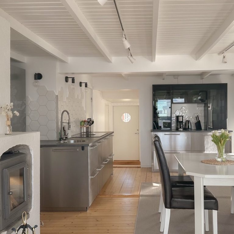Moderne Küche mit Esstisch, Holzdielenboden und viel Tageslicht.