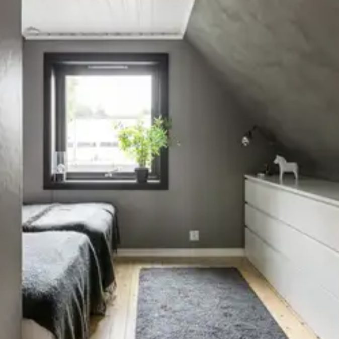 Klein und modernes Schlafzimmer mit zwei Betten, Fenster und minimalistisch skandinavischer Einrichtung.
