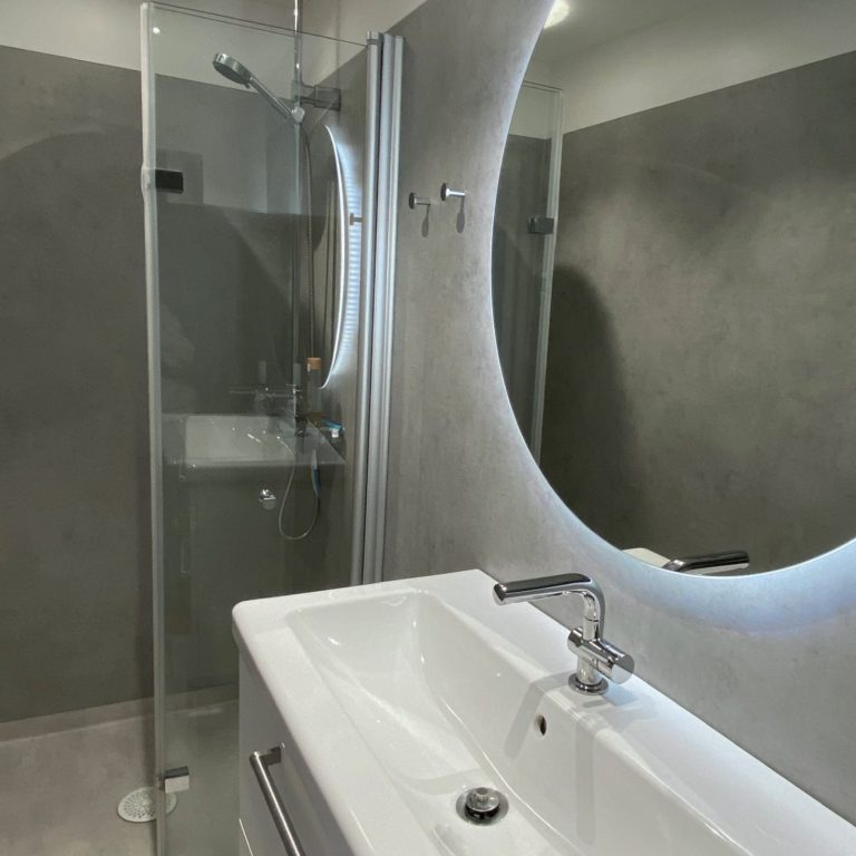 Modernes Badezimmer mit Dusche, Waschtisch und Spiegel in neutralen Farben.