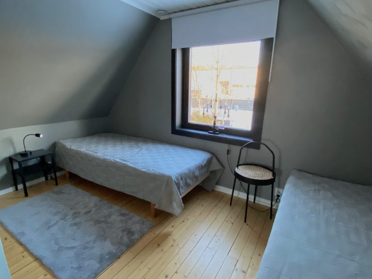 Gemütliches Schlafzimmer mit zwei Einzelbetten und einem Fenster, hell und skandinavisch eingerichtet.