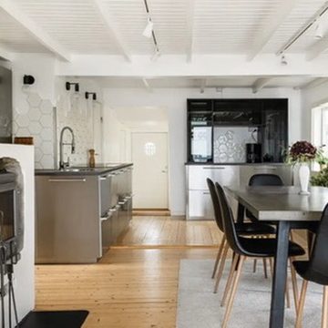 Moderne Küche mit Esstisch, Holzdielenboden und viel Tageslicht.