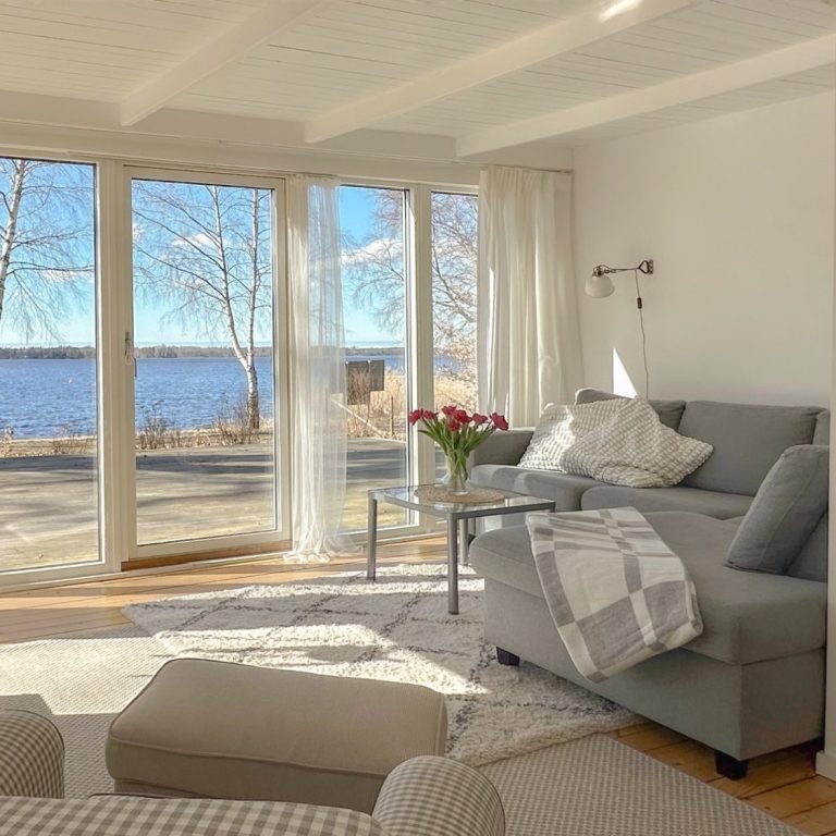 Helles Wohnzimmer mit Blick auf den Schnee und den See durch große Fensterfront.