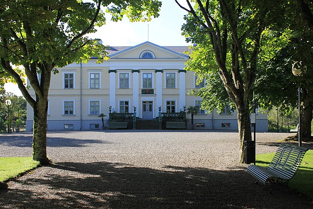 Historisches Gebäude umgeben von Bäumen, mit einer einladenden Auffahrt.